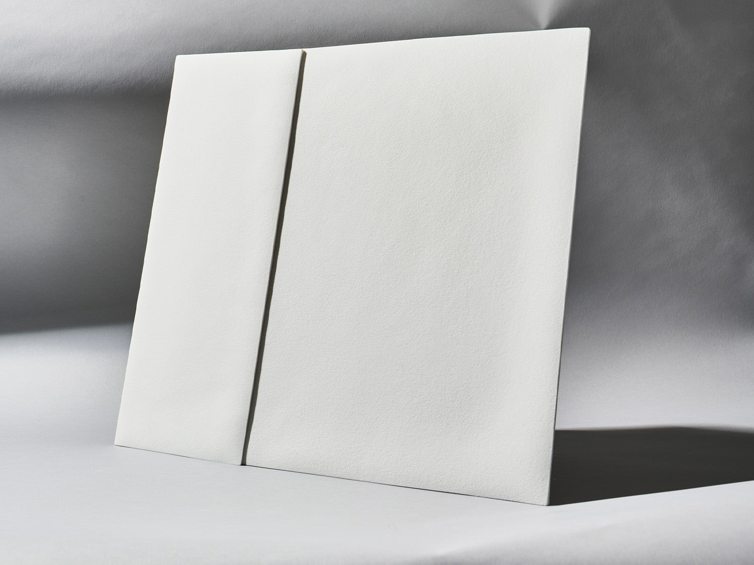 Unglasierte Porzellanfliesen der Serie Lightscape, schräg aufgestellt, mit sanftem Lichtverlauf über der strukturierten Oberfläche.

Unglazed porcelain tiles from the Lightscape series, placed at an angle, with soft lighting across the textured surface.