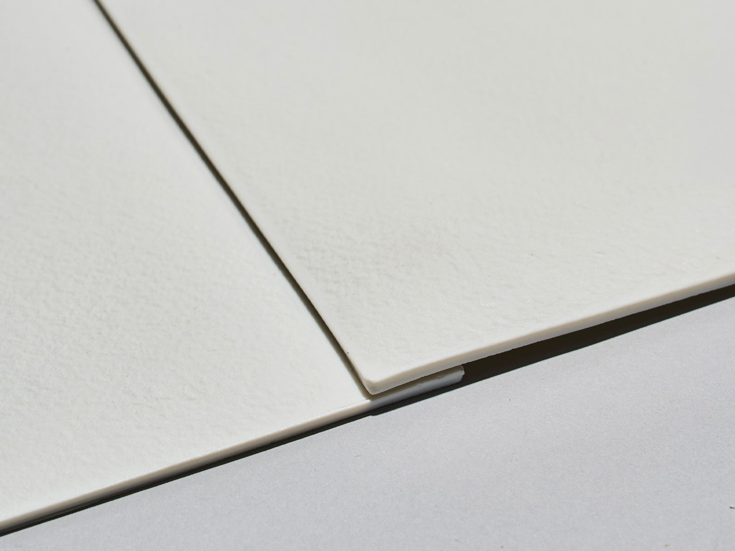 Nahaufnahme zweier unglasierter Lightscape-Fliesen mit spürbarer, matter Struktur und geraden Kanten.

Close-up of two unglazed Lightscape tiles with a tactile matte texture and straight edges.