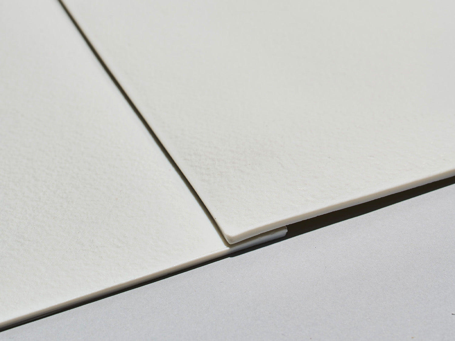 Nahaufnahme zweier unglasierter Lightscape-Fliesen mit spürbarer, matter Struktur und geraden Kanten.

Close-up of two unglazed Lightscape tiles with a tactile matte texture and straight edges.