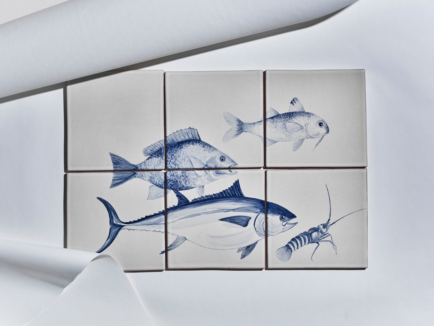 Sechsteiliges Fliesenbild mit handgemalten Meeresmotiven in Blau auf hellem Grund: Fische und ein Krebs.

Six-tile mural with hand-painted marine motifs in blue on a light background: fish and a crustacean.