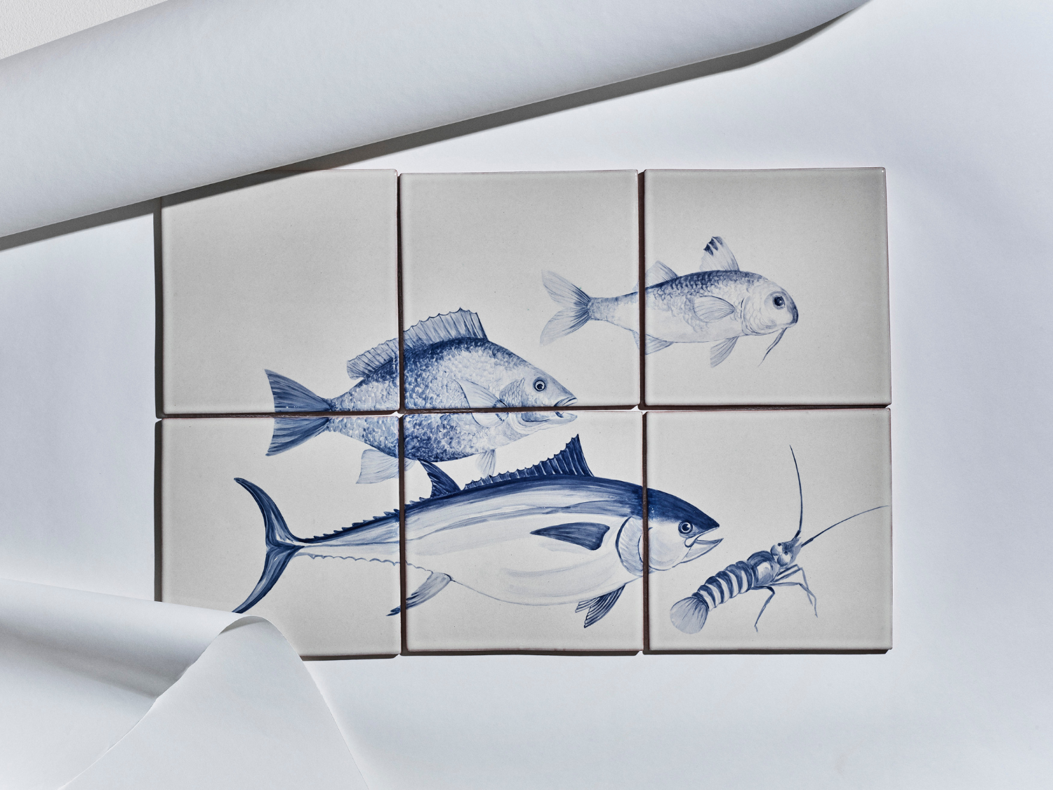 Sechsteiliges Fliesenbild mit handgemalten Meeresmotiven in Blau auf hellem Grund: Fische und ein Krebs.

Six-tile mural with hand-painted marine motifs in blue on a light background: fish and a crustacean.