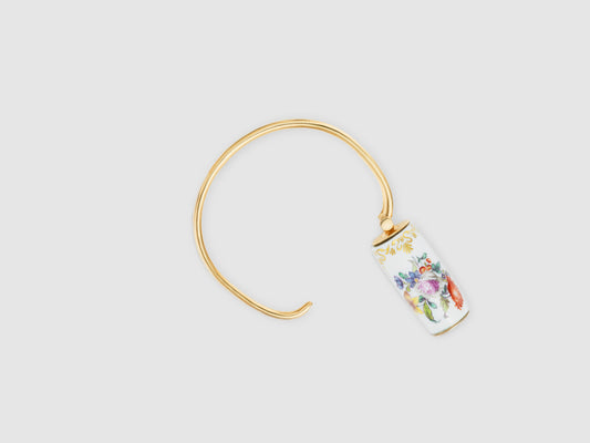 Geöffneter Armreif mit drehbarem Porzellan-Zylinder und goldfarbenem Verschluss.

Open bangle showing the rotating porcelain cylinder and gold-toned closure.