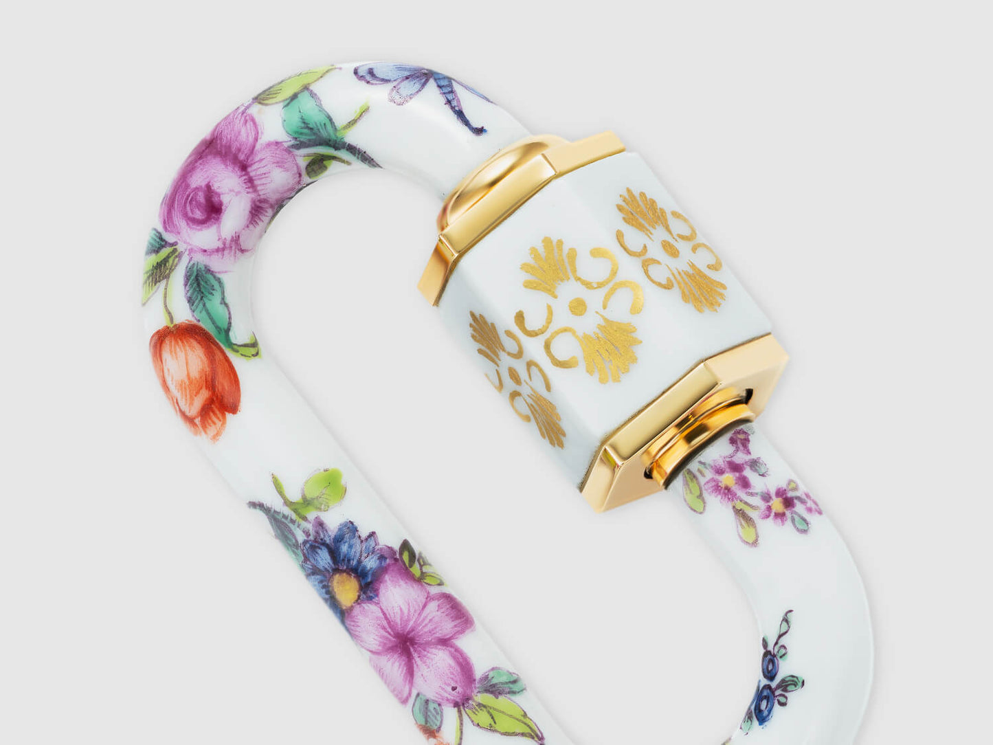 Detailaufnahme der vergoldet anmutenden Hülse mit Ornament und umlaufender Blumenmalerei auf dem Porzellan-Schloss.

Close-up of the gold-toned ornamental sleeve with continuous floral painting on the porcelain lock.