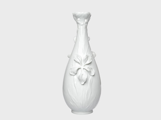 Weiße Porzellanvase mit glänzender Oberfläche und floralen Reliefdetails auf neutral hellgrauem Hintergrund. Die bauchige Form wird durch eine große Blütenapplikation auf der Vorderseite und eine dekorativ geformte, blütenartige Öffnung am Hals ergänzt.

White porcelain vase with a glossy finish and floral relief details on a neutral light gray background. The rounded body features a large flower applique on the front, while the neck is finished with a decorative, blossom-shaped opening.
