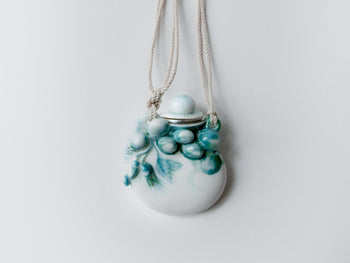 Handgefertigter Porzellanflakon mit türkisfarbenen Beerenreliefs und Kordel aus der Kooperation von Nymphenburg und Ole Lynggaard Copenhagen.

Handcrafted porcelain flask with turquoise berry reliefs and cord from the collaboration between Nymphenburg and Ole Lynggaard Copenhagen.