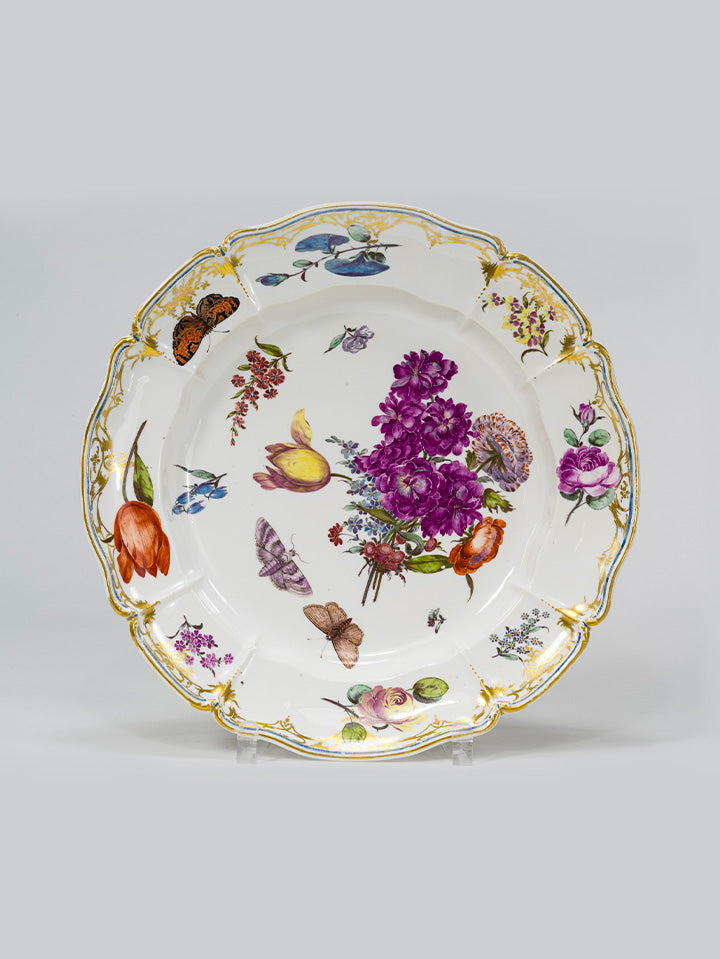 Porzellanteller mit floraler Malerei, goldverziertem Rand und filigranen Schmetterlingen.

Porcelain plate with floral motifs, gilded rim, and delicate butterflies.