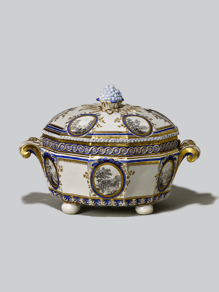 Porzellan-Terrine mit kobaltblauer und goldener Verzierung, Landschaftsmedaillons in Grisaille und plastischem Traubenknauf auf dem Deckel, Serie „Perl“.

Porcelain tureen with cobalt blue and gold decoration, grisaille landscape medallions and sculptural grape finial on the lid, “Perl” series.